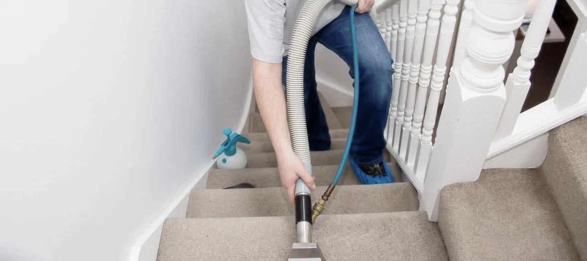 Technician deep-cleaning wall-to-wall carpet on a residential staircase